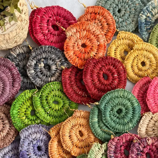 Colorful woven round earrings in various shades arranged on a white surface.
