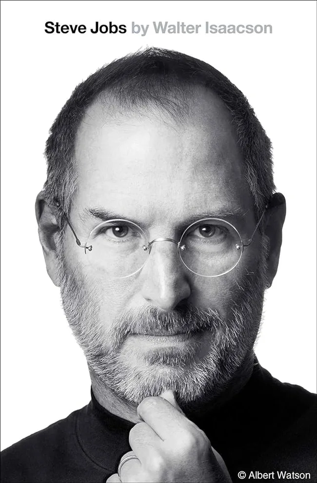 Black and white portrait of a man with glasses, chin resting on hand; cover of "Steve Jobs" by Walter Isaacson.