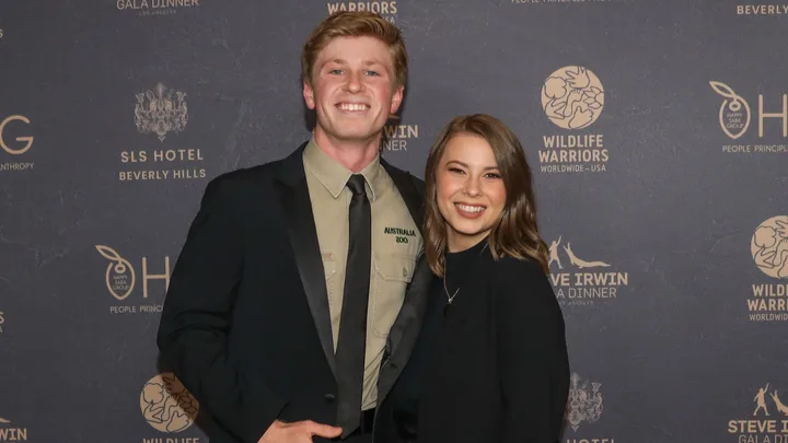 Young man and woman smiling in front of a Wildlife Warriors event backdrop.