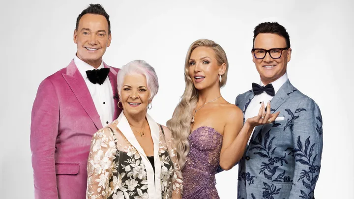 Four people dressed in formal attire, smiling against a plain background.