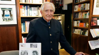 Elderly man in a bookstore with a book titled "Prince Michael of Greece" on display.