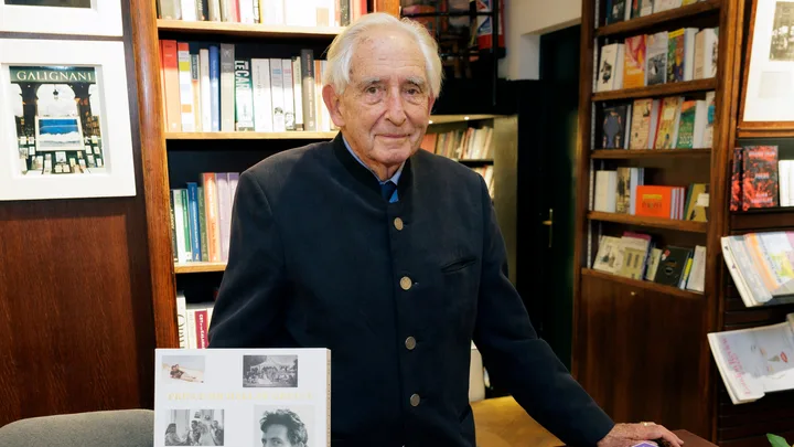 Elderly man in a bookstore with a book titled "Prince Michael of Greece" on display.