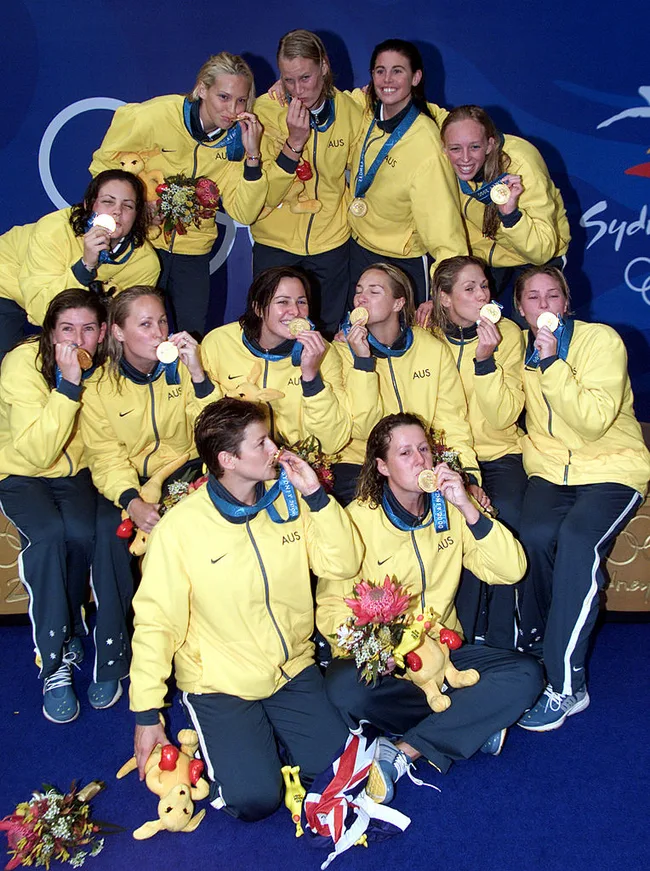 Australian women's Olympic team celebrating with gold medals at the 2000 Sydney Olympics, wearing yellow jackets.