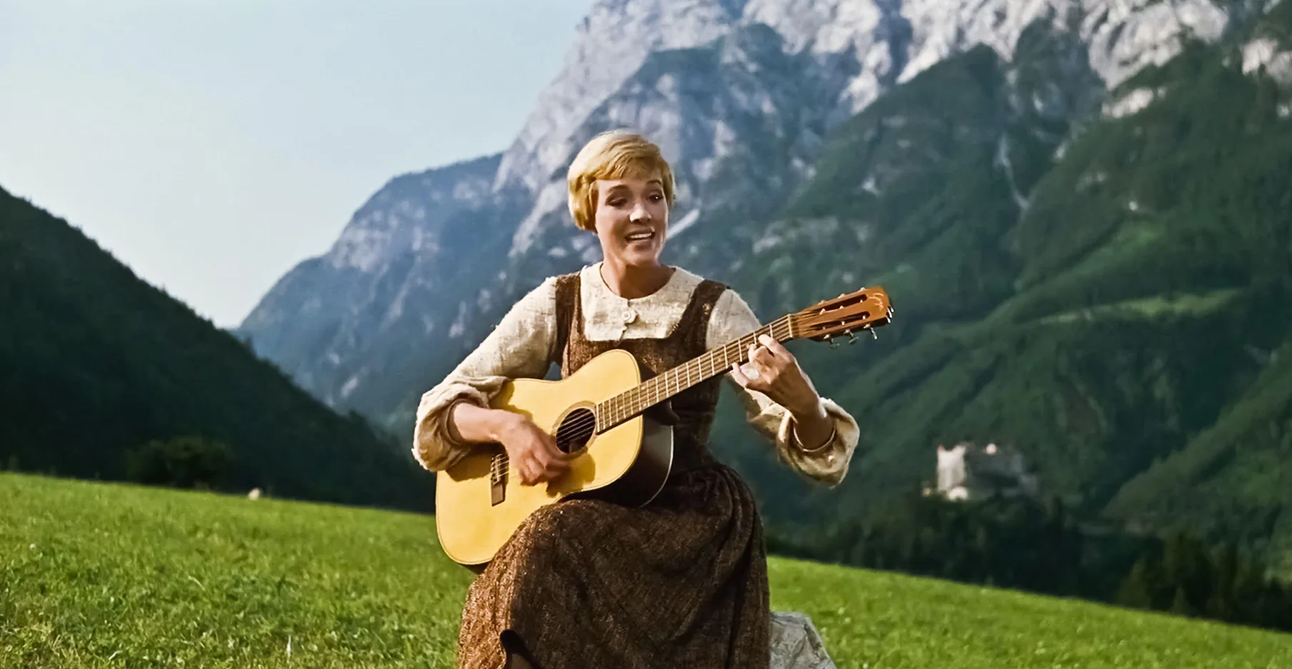 Julie Andrews in The Sound of Music. She is playing a guitar and singing.