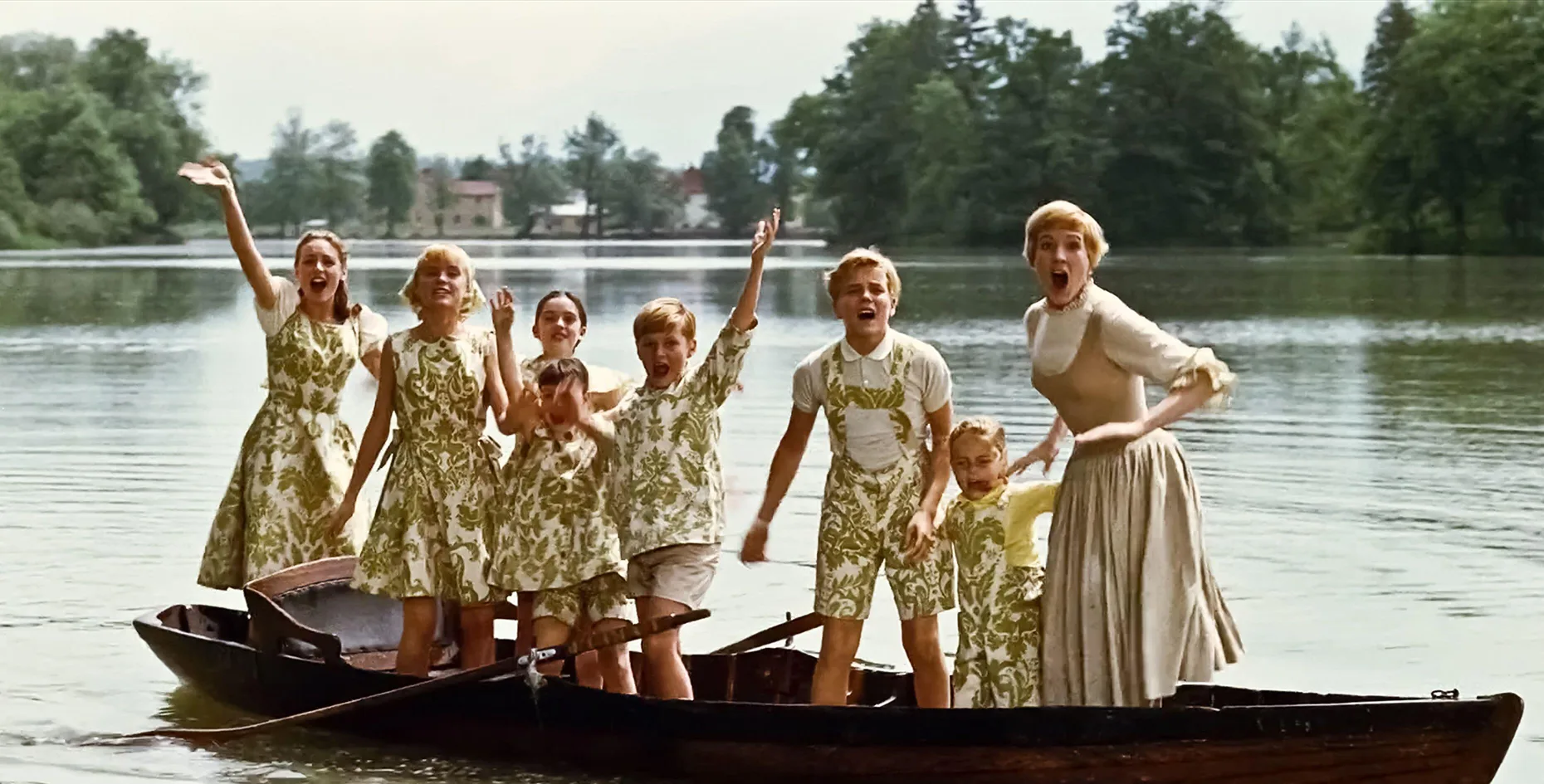 Julie Andrews as Maria, and the seven child actors in The Sound of Music, stand in a canoe in the middle of a lake.