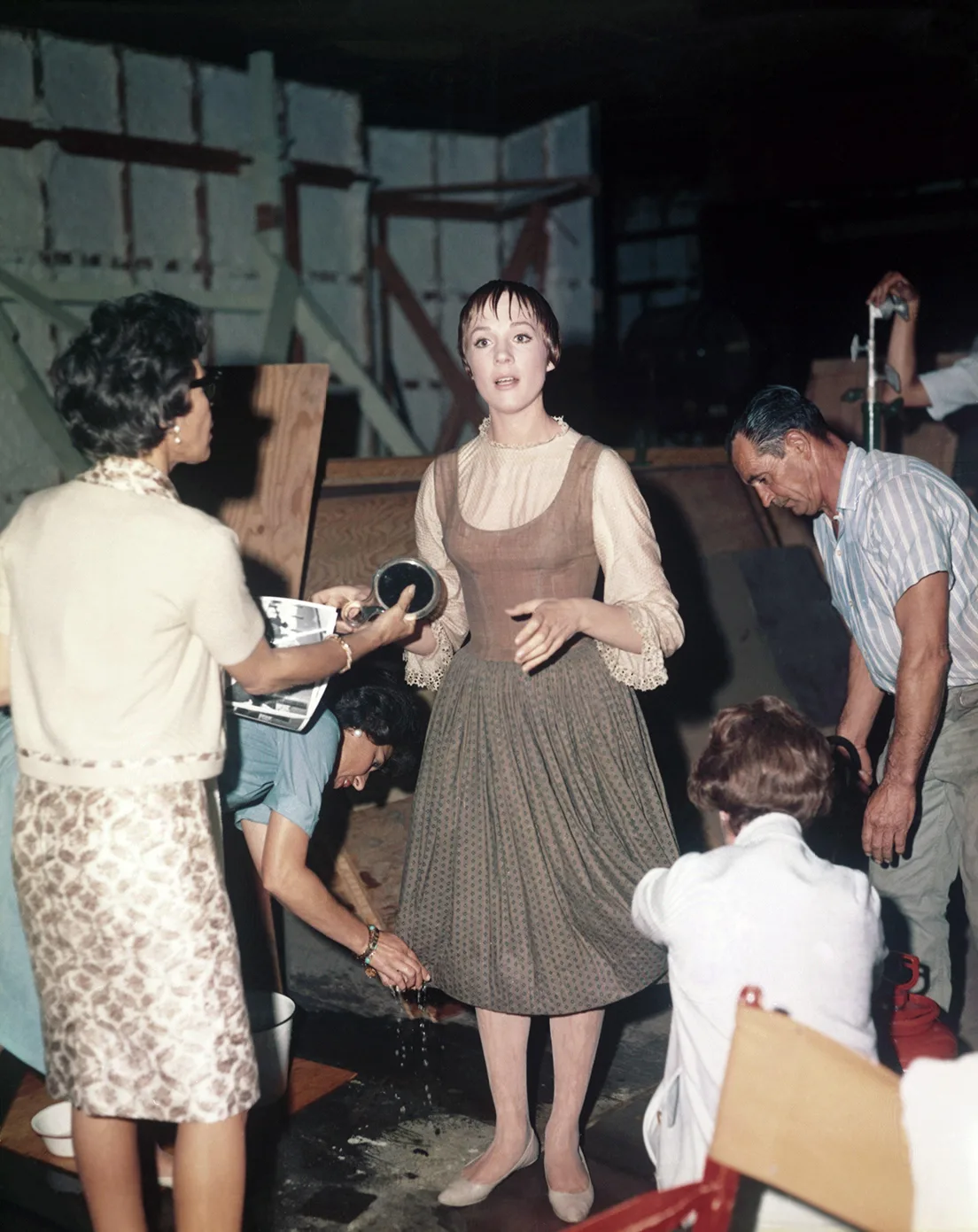 Photo of Julie Andrews who is sopping wet and is having her clothes wrung out by staff.
