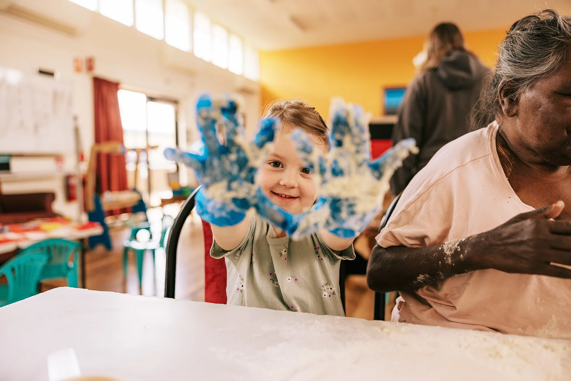 A young girl holds up her gloved hands to the camera.