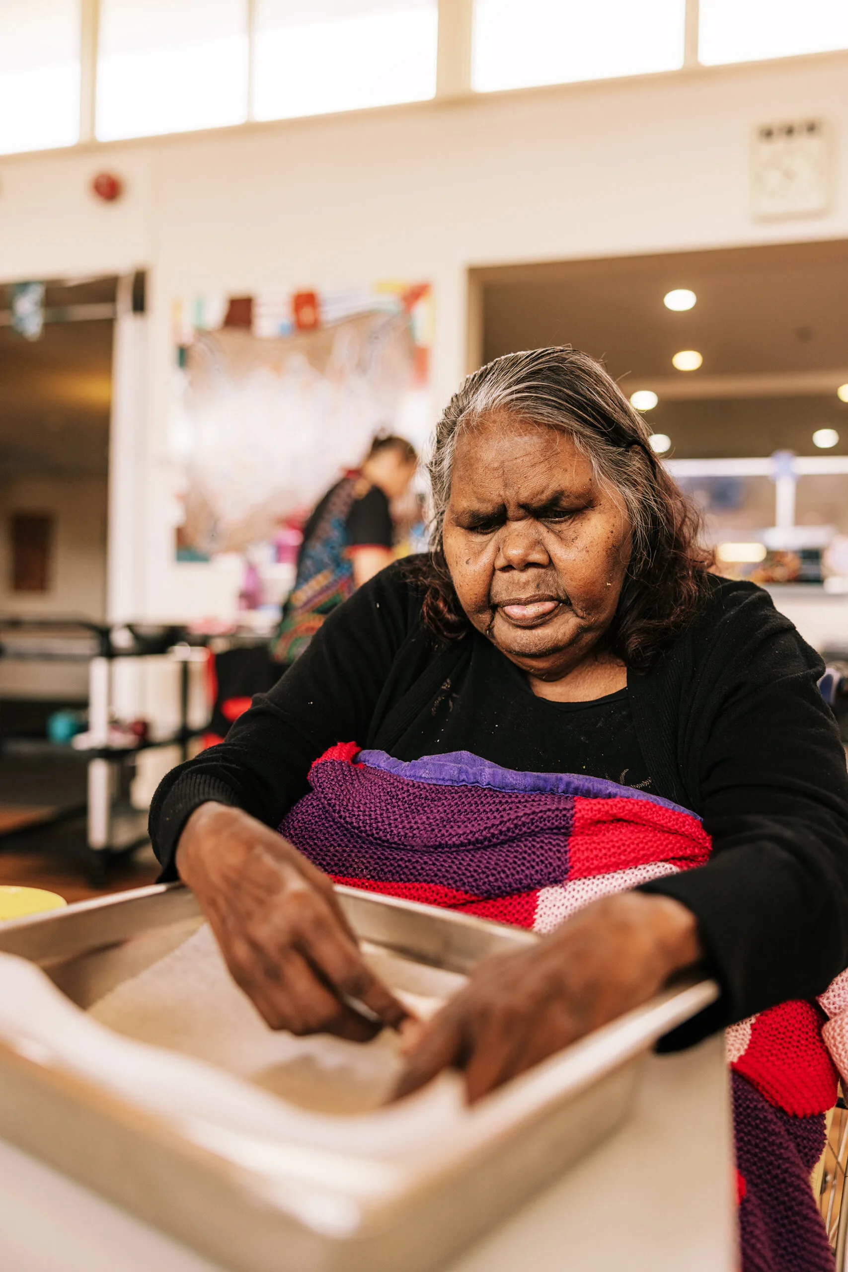 An older Aboriginal woman preparing food.
