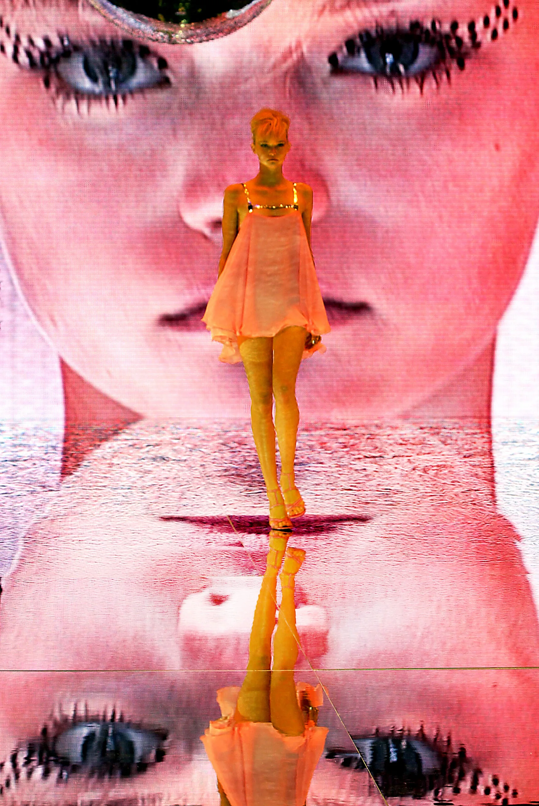 model walks down catwalk in a short orange dress