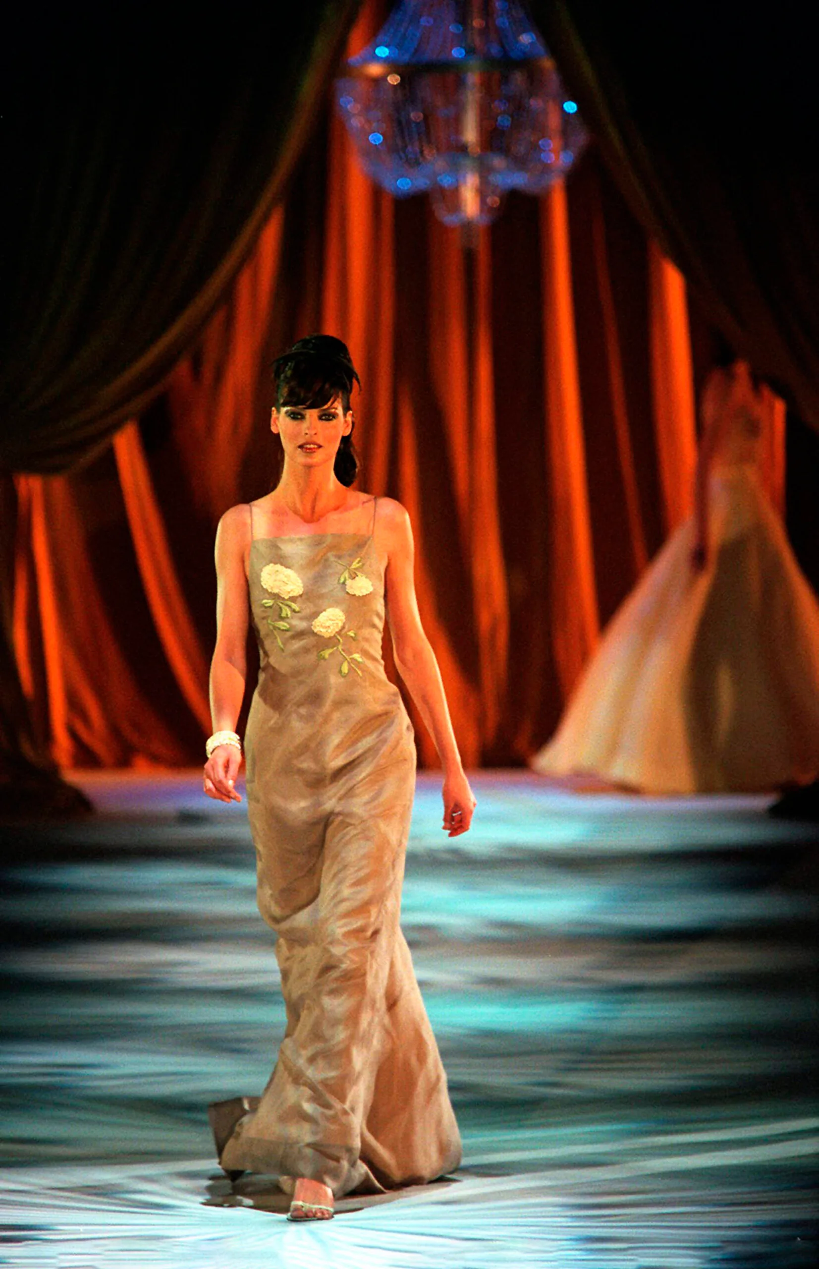 A woman in a floor-length dress and a beehive hairdo walking the runway at fashion week in australia