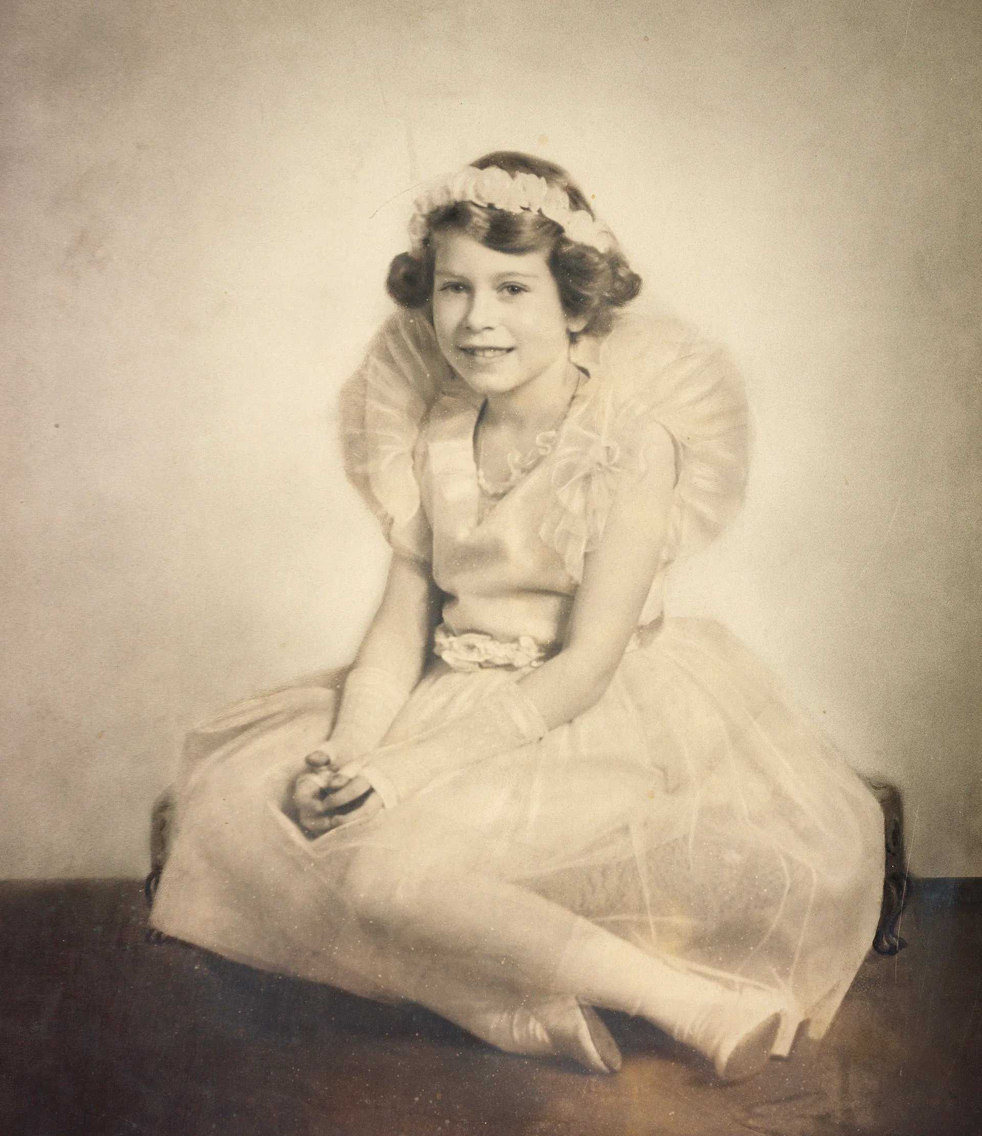 Queen Elizabeth II as a young girl in a tulle dress with a flower crown