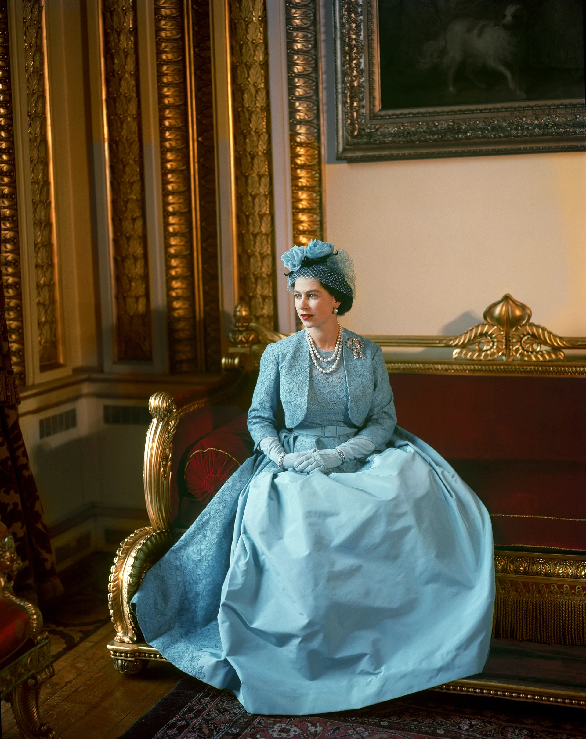 Queen Elizabeth II in a blue gown, jacket and fascinator