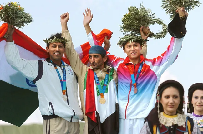 Athletes on Olympic podium holding flags and wreaths, celebrating a medal victory.