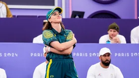 A person in a green and yellow uniform crosses arms at the Paris 2024 event.