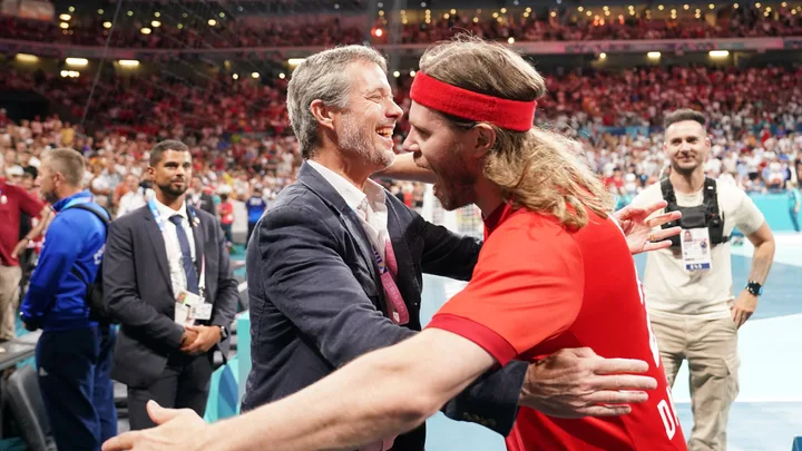 Two people embracing in celebration at a sports event, surrounded by a cheering crowd.