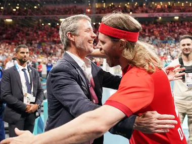 Two people embracing in celebration at a sports event, surrounded by a cheering crowd.