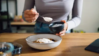 Woman eating yoghurt and cereal for breakfast