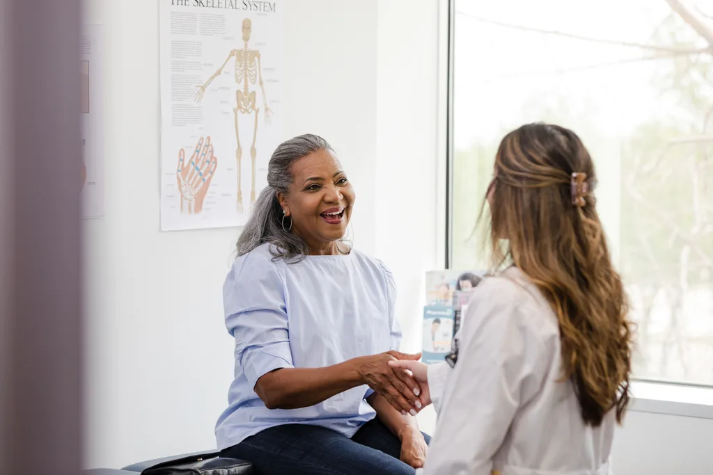 A woman shaking hands with her doctor.