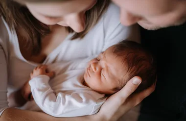 woman and man cradling a newborn baby