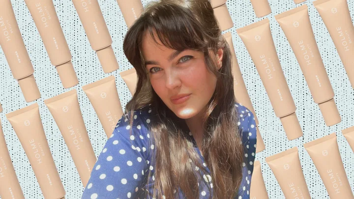 Woman in polka dot shirt against backdrop of Holme Beauty primer tubes.
