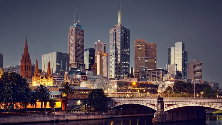Melbourne skyline at dusk with illuminated city buildings and St. Paul's Cathedral.