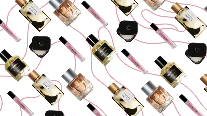 Various perfume bottles and vials with pink trails on a white background.