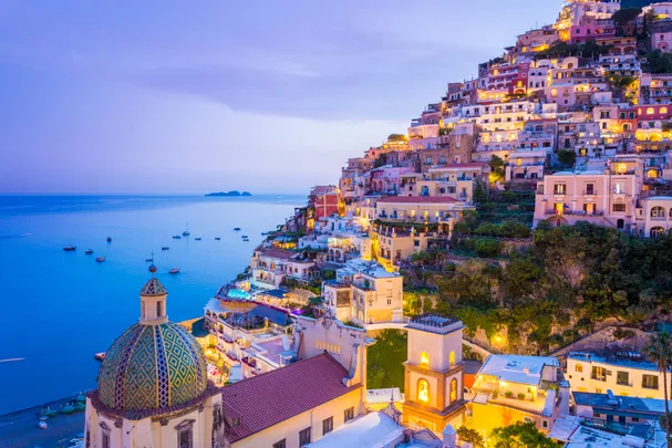 Colorful hillside buildings overlooking the sea at sunset in Positano, Italy.