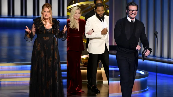 Three presenters on stage at an award show, one in a black dress, another in red with a white tux, and a man in black.