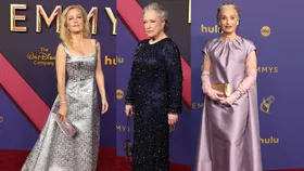 Three women in elegant evening gowns standing on the red carpet at the Emmy Awards.