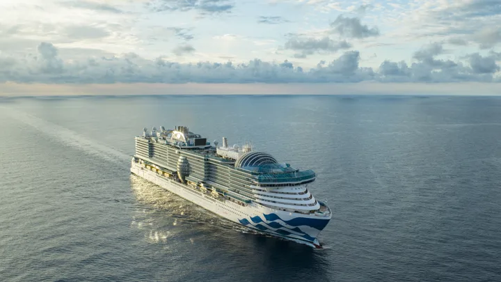 Aerial view of the Princess Cruises ship sailing on the open sea under a partly cloudy sky.