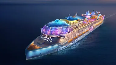 A futuristic cruise ship named "Icon of the Seas" sailing at night with vibrant lights illuminating its decks.