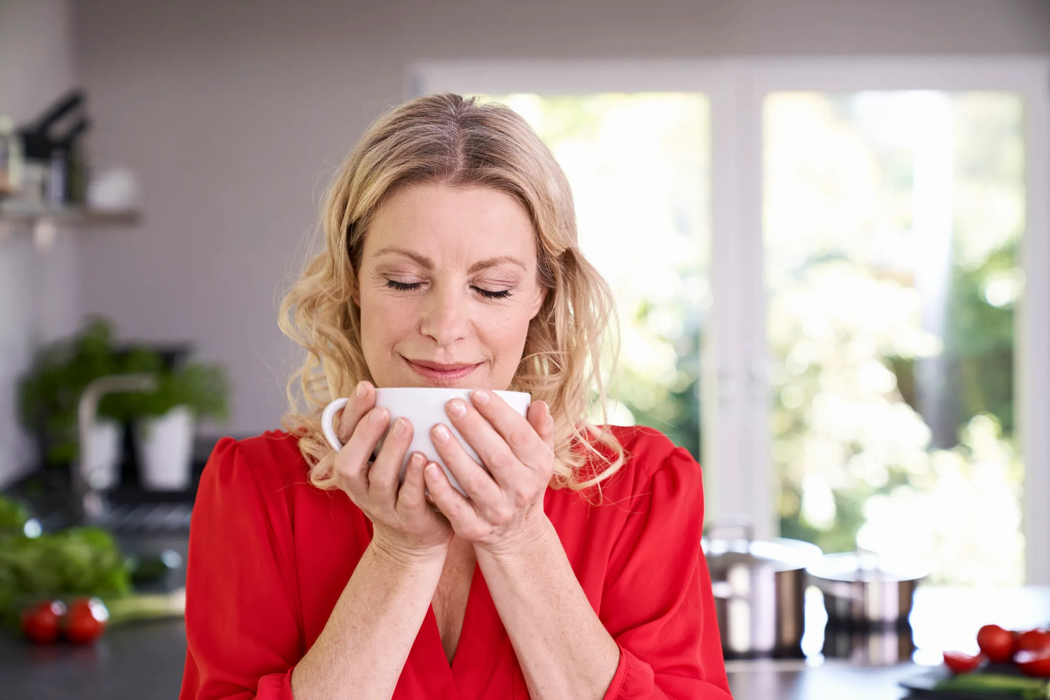 Woman enjoying cup of coffee in kitchen