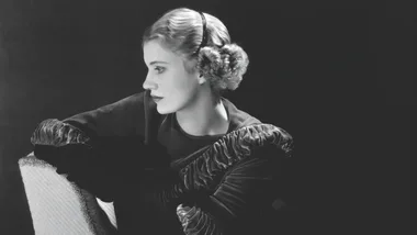 Black and white portrait of a woman in profile with headband and wavy hair, looking thoughtfully into the distance.