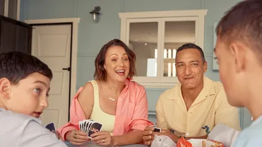 Celeste Barber, husband Api Robin and their sons sit and play a card game.