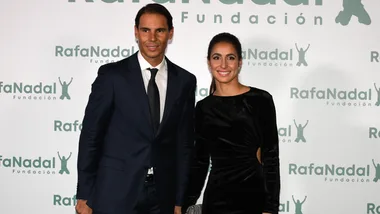 Two people smiling at a Rafa Nadal Foundation event, standing in front of a logo backdrop.