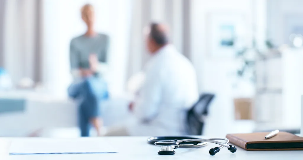 A blurred image of a doctor and patient talking.