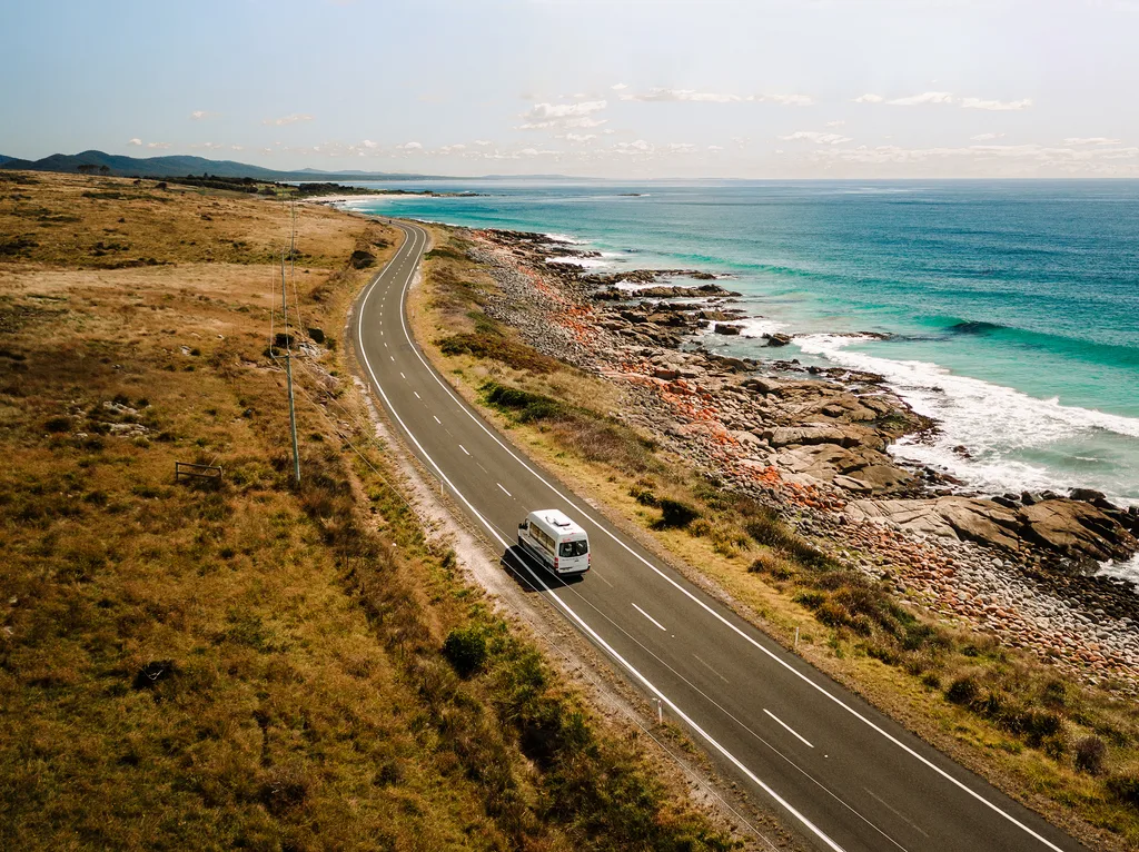 A campervan driving along a coastal road.
