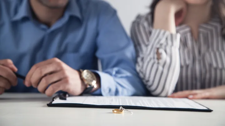 Is January Divorce Month? A man and woman sit in front of divorce papers with their rings off