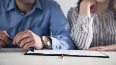 Is January Divorce Month? A man and woman sit in front of divorce papers with their rings off