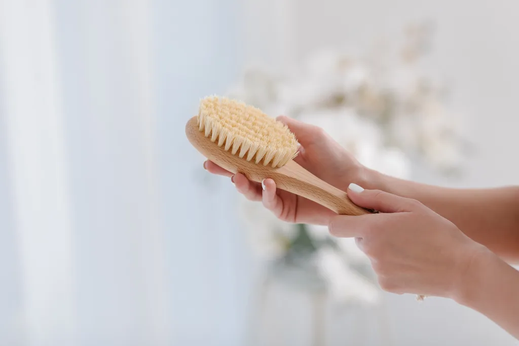 A woman holding a dry body brush.