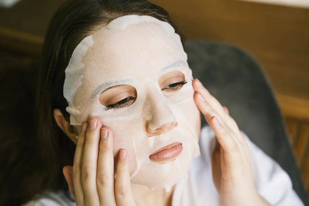 A woman putting on a sheet mask.