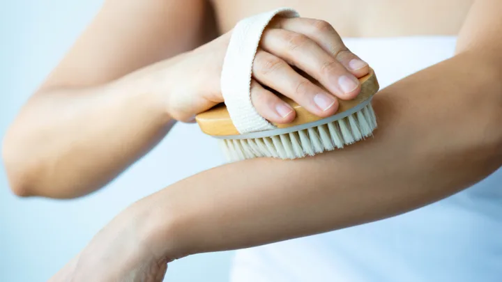 A woman dry brushing her skin.