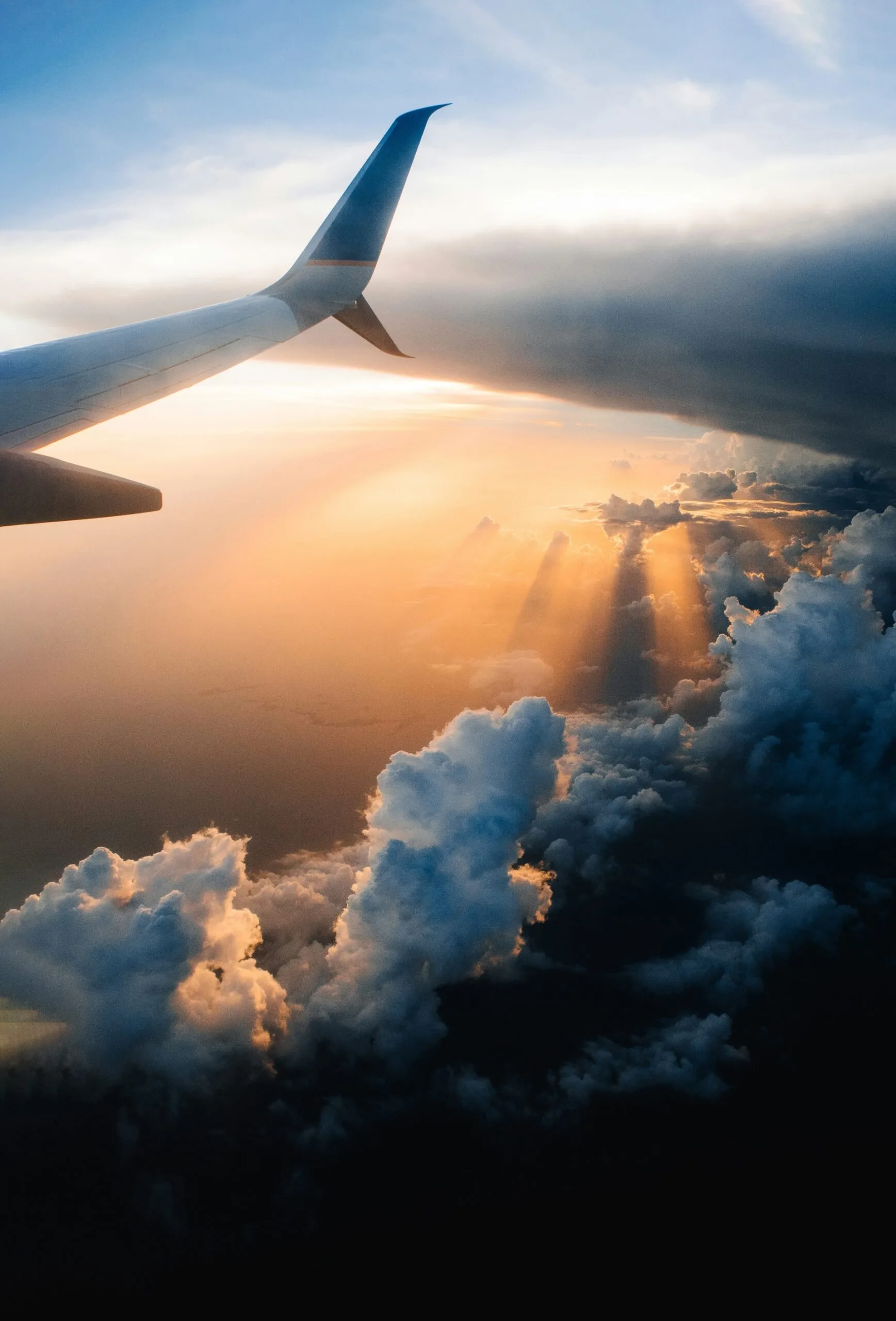 Aeroplane wing over a sunlit, cloudy sky
