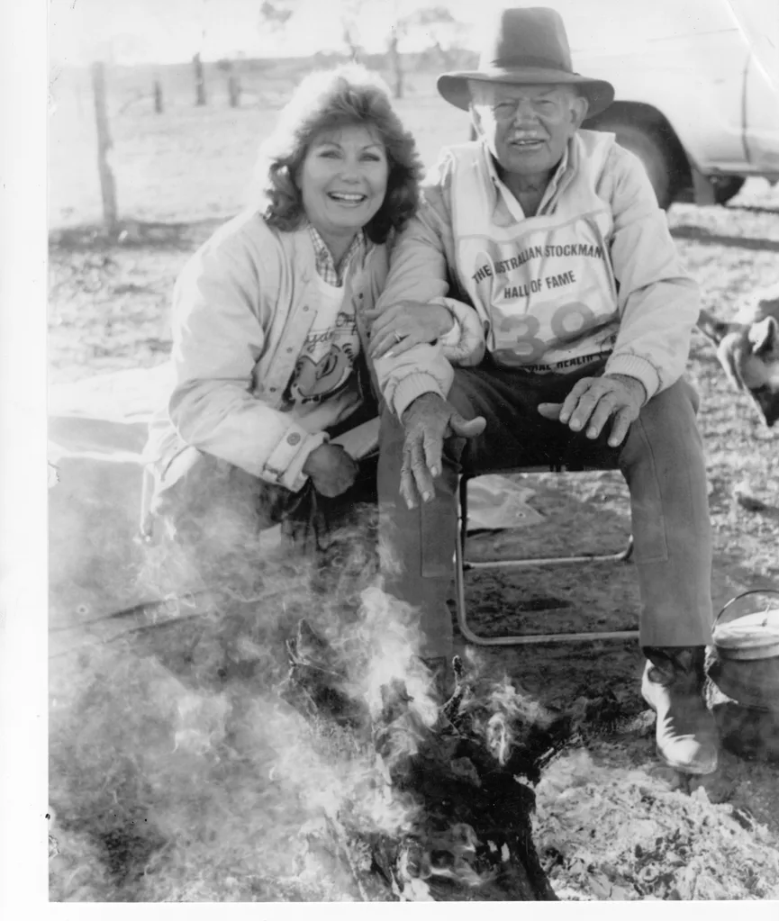Author Di Morrissey kneels besides R.M. Williams.