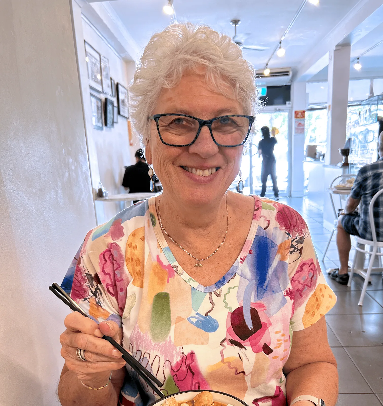 A woman with glasses smiles.
