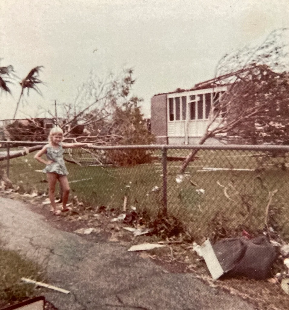 A young girl stands at a fence near the wreckage of a building in Darwin.