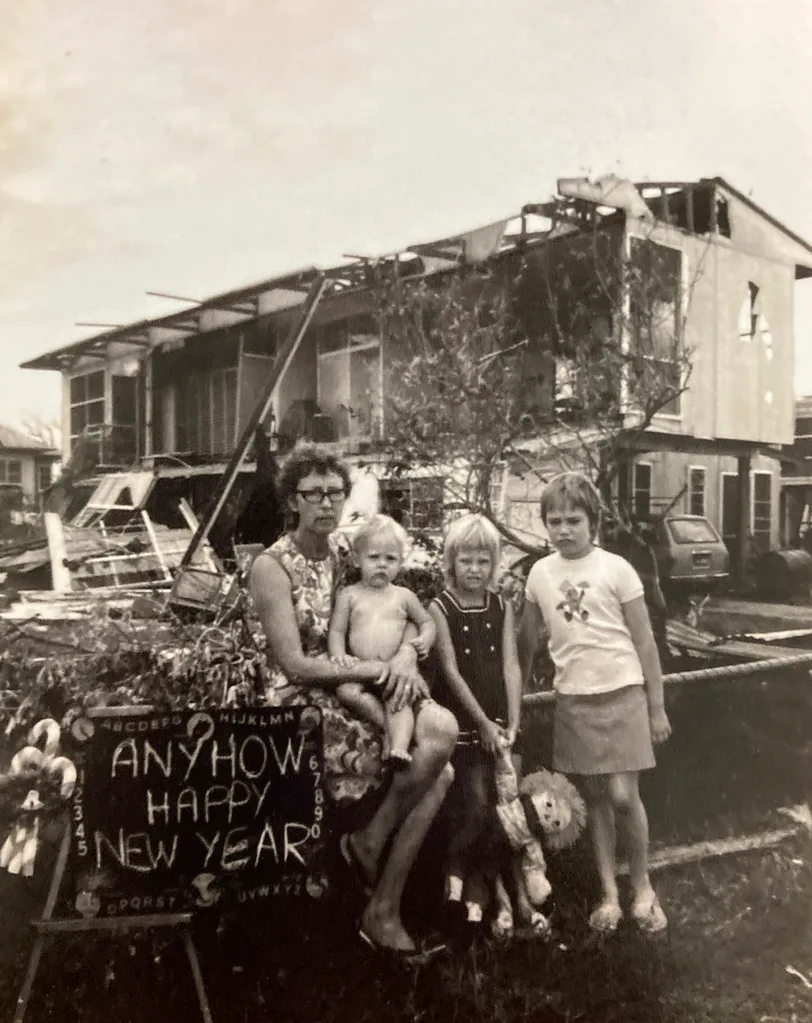 Family outside their destroyed home in Darwin after Cyclone Tracy with a sign that says, 'Anyhow. Happy New Year.'