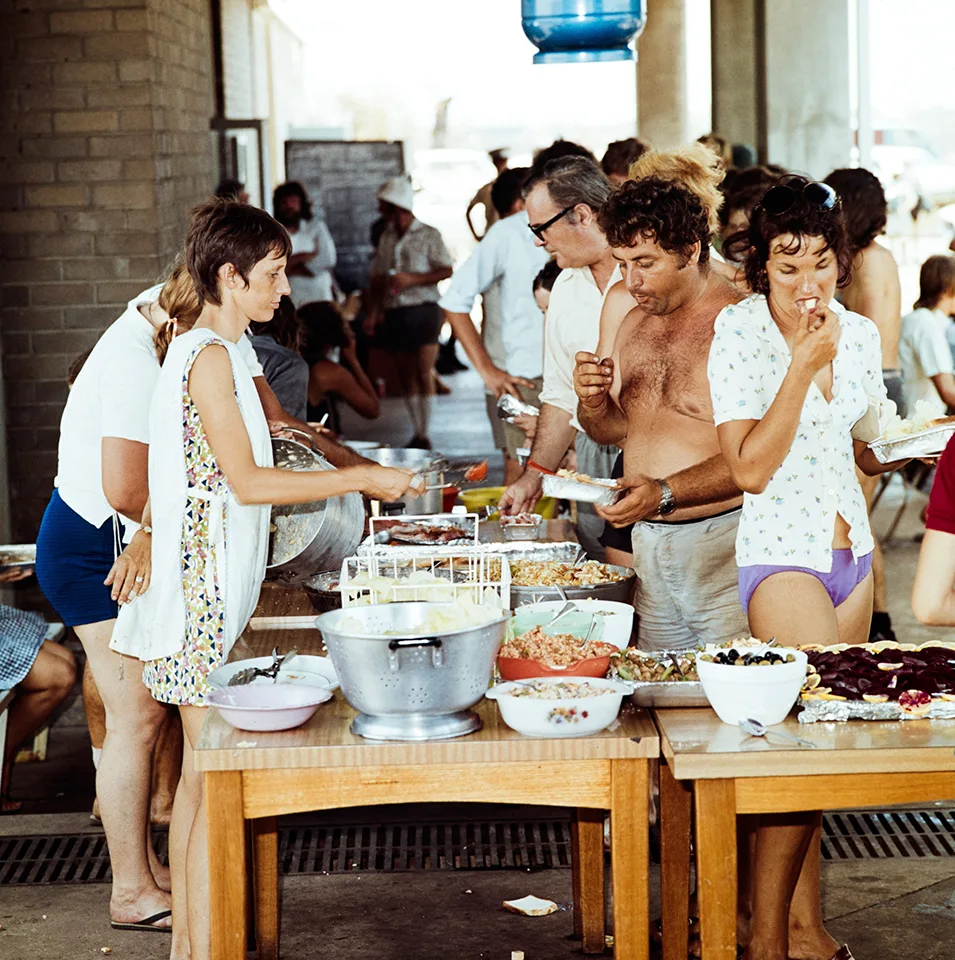 People queuing by tables of food.
