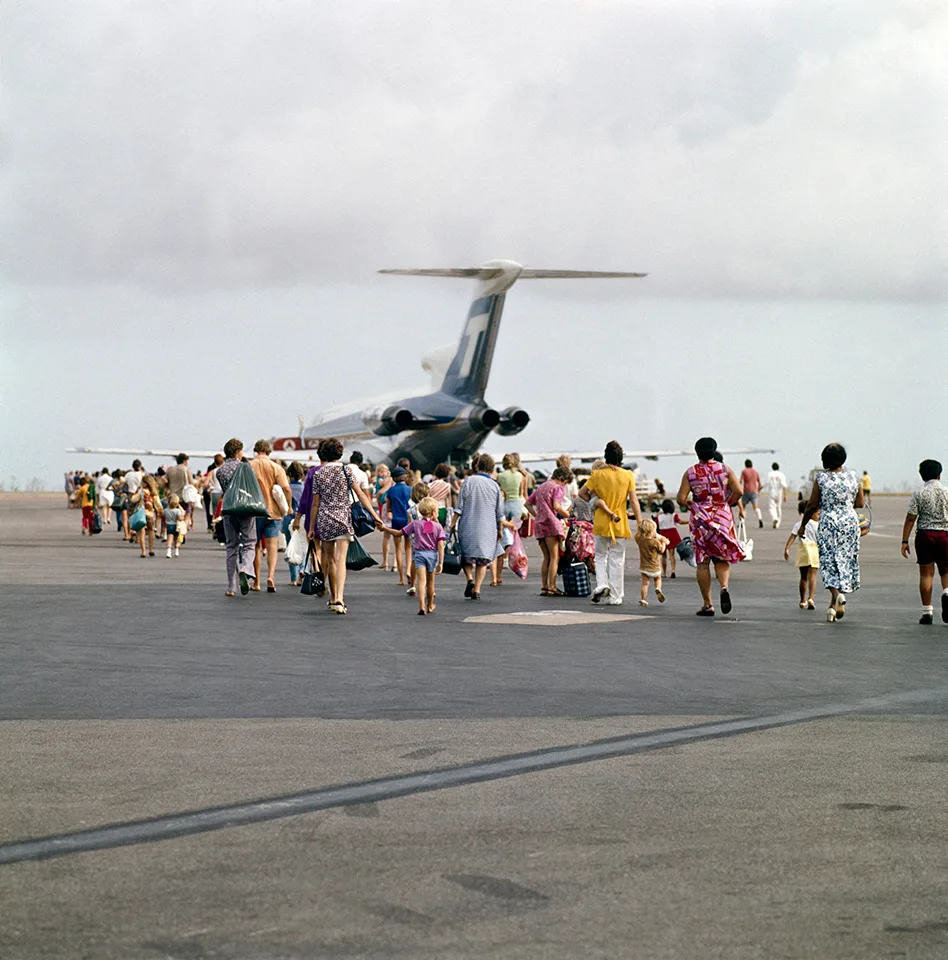 A crowd of people walk towards a plane.