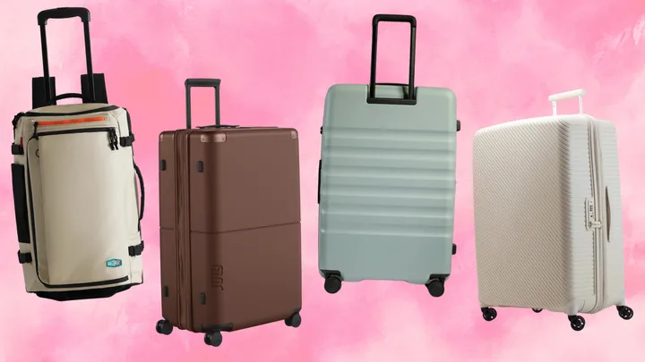 Four different styles of travel luggage arranged against a vibrant pink watercolour background. From left to right: a beige Bagsmart Blast 43L Roller Backpack with orange accents, a dark brown July Checked Plus Expandable suitcase, a mist-blue Antler Icon Stripe large suitcase, and a cloud-white Nere Bondi 80cm hardshell suitcase.
